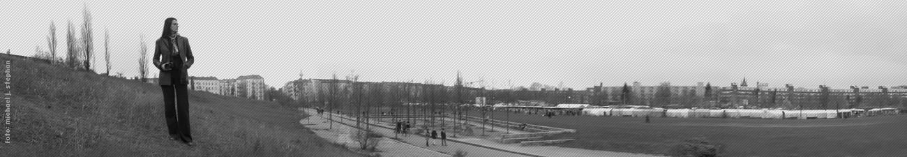 Schwarzweiß-Panorama eines Parks, im Vordergrund eine Frau mit Kamera auf einem Hügel